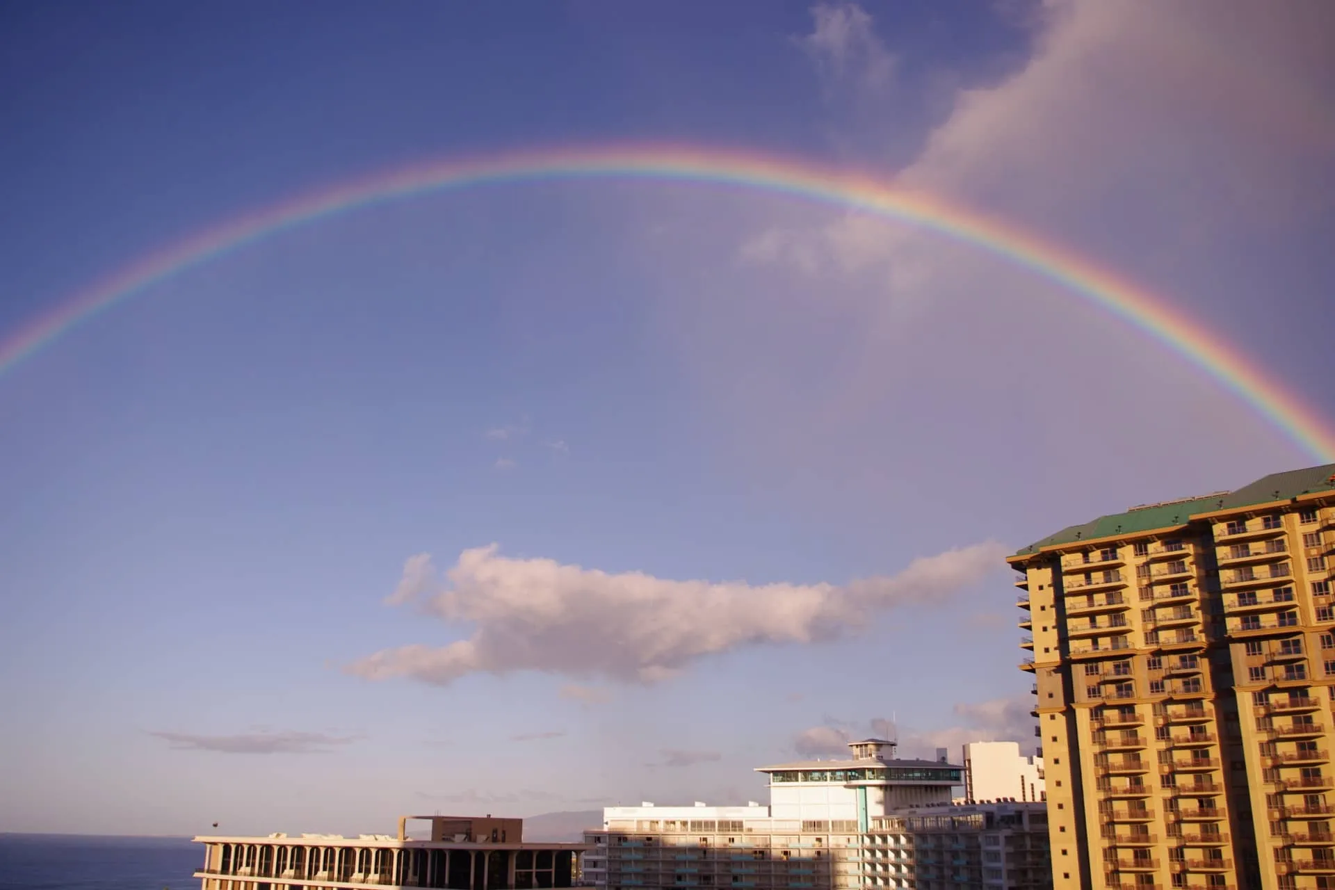 雨上がりのホノルルの空にかかる虹と高層ホテル